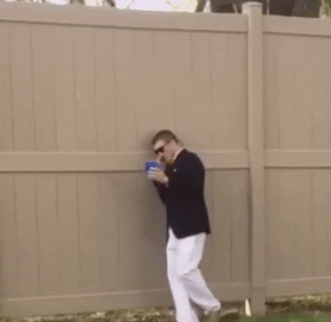 a man stumbles drunkenly against a fence