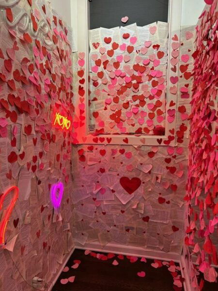 A room with pink lighting and paper hearts on the walls