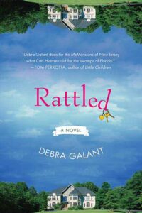 Rattled is in pink text in the middle with an image of a house in some trees that's mirrored on the top and bottom of the cover
