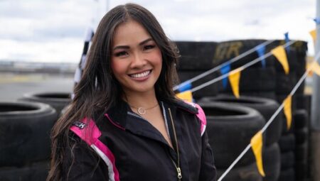 Jenn stands in front of some tires on a racetrack