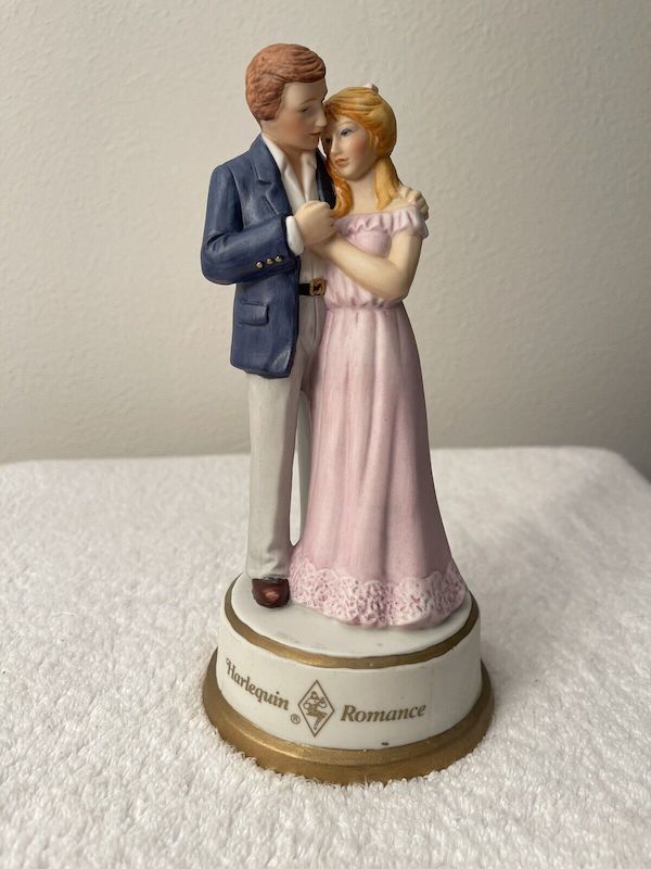 A picture of the Passionate Enemies music box - a porcelain couple embraces in the same pose as the cover, only his jacket is blue, he does not have chest hair and they both look very very young