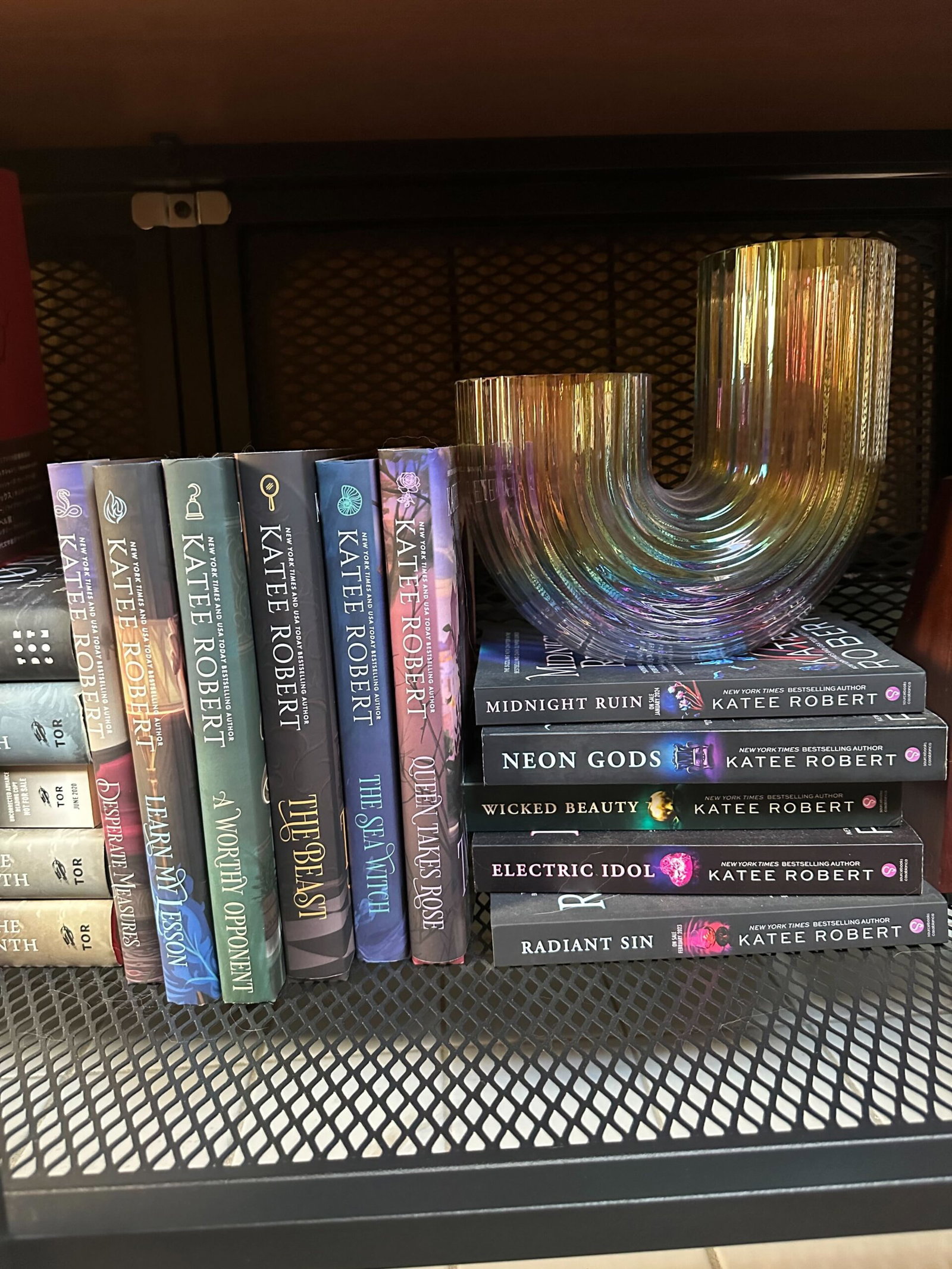 Wicked Villains, a stack of hardcovers on a bookshelf with a rainbow, u-shaped vase