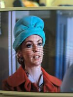Actress Miranda Raison is wearing a turquoise hat that kind of looks like a crumpled stocking smushed onto her head. It's absurd. It works. I love it.