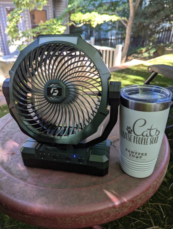 A picture of the fan on a red metal table outside next to a Pawfee shop insulated coffee cup 