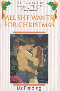 A woman with red hair and a maillot swimsuit embraces a guy in swim trunks against a cabin with a bow on it