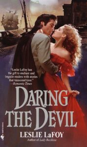 Daring the Devil is a photograph cover with a woman with big curly blonde hair and a red off the shoulder dress backlit by the Touched by an Angel light, being embraced by a white guy with a mullet, a white shirt, and a CAPE with a ship in the background 