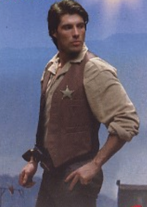 A close up of the man showing the gun stuck in his pants with the barrel pointed at his dick.