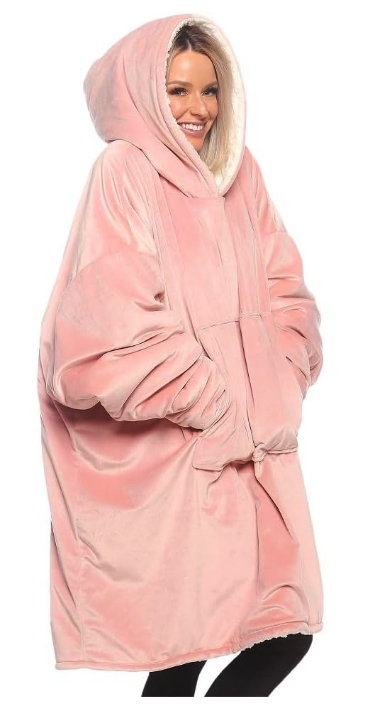 A white woman in a giant fleece hoodie that comes down to her knees. it has a kangaroo pocket in the front