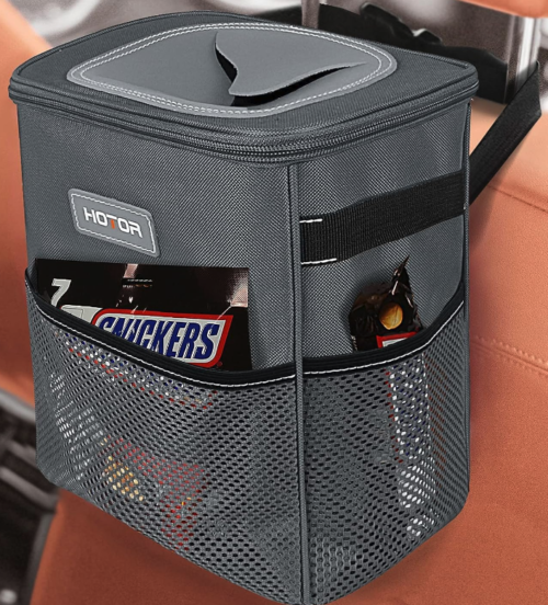 A grey car trash can with mesh sides and a large opening at the top, strapped to the back of the headrest