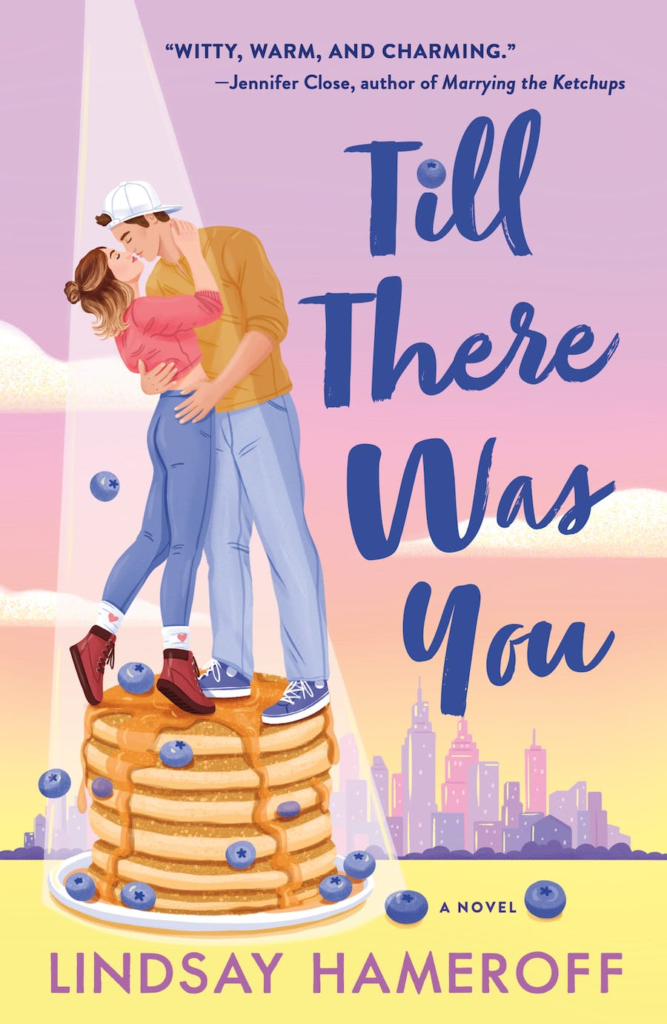 Till There Was You by Lindsay Hameroff. An illustrated cover of a couple kissing on top of a stack of pancakes smothered in syrup and topped with blueberries. She is wearing jeans, brown boots, and a pink salmon colored sweater. Her hair is half in a bun and half down. He is wearing jeans, blue sneakers, a brown sweater, and a white backwards baseball cap. The sky blends from purple to pink to orange to yellow and the shape of a city lingers in the background.