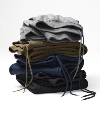 A folded pile of sweatpants in grey, olive, blue and black