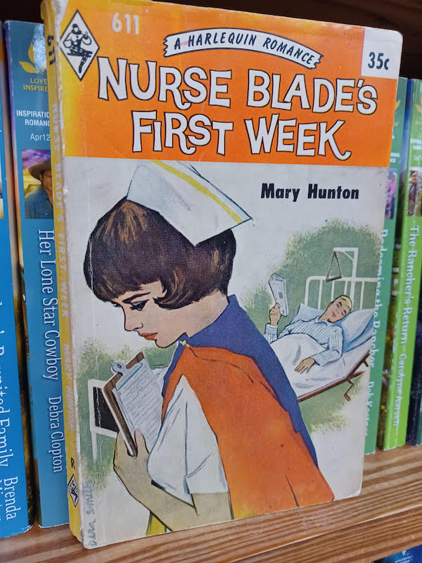 Harlequin 611 Nurse Blade's First Week by Mary Hunton An orange banner at the top with the title and then an illustration of a nurse looking forlorn wearing a blue and orange uniform and white cap. Behind her is a blonde man reading a newspaper in a hospital bed sort of leering at her 