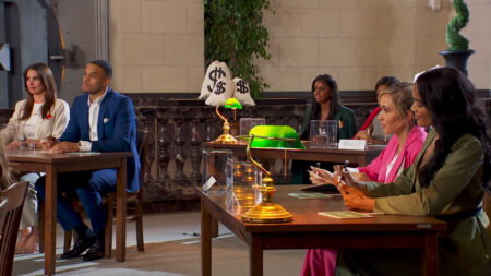 Grant and the women sit at tables at Bachelor Finance School