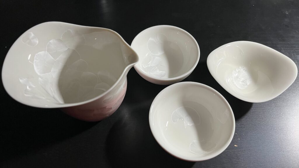 Top view of the teapot and three teacups on a black desk, showing the mother of pear-like splotches on the inside.