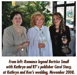 Bertrice Small, Kathryn Falk, and Carol Stacey at Kathryn's wedding, NOvember 2008. Bertrice has short dark hair and is wearing a gold and beige dress. Kathryn has red hair and is wearing atiara, a blue cape and a blue gown. 