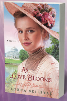 As Love Blooms, an inspirational with a white woman with blonde hair on the cover wearing a pink and brown dress and a fabulous chapeau tilted to the side with flowers around the brim in pink 