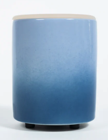 A blue glazed cylindrical wax warmer that fades from light to deep blue top to bottom. It has a thin beige ring at the top where the wax goes 