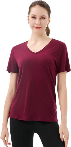 a white woman with brown hair pulled back in a ponytail is wearing a burgundy v neck shirt and black pants 