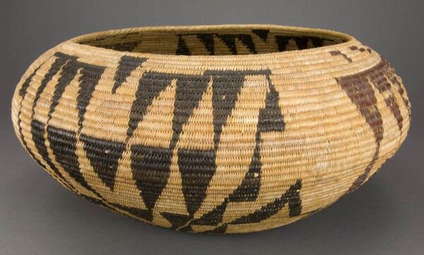 Full color photo of one of Ta-bu-ce's baskets. It is light brown with dark brown triangular shapes.