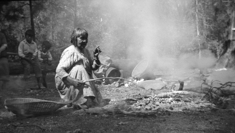 Ta-bu-ce teaches visitors how to cook over a fire