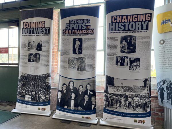 visitor center display about LGBTQIA+ workers in three banners labeled COMING OUT WEST, Gathering spots in San Francisco, and Changing History. There are black and white photos printed on all three banners