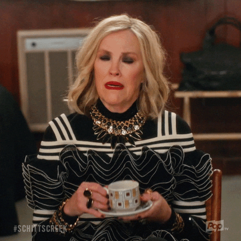 Moira from Schitt's Creek shakes her head while holding a tea cup