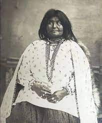 Black and White photo of Tze-gu-juni seated, long black hair unbound, wearing a white patterned top