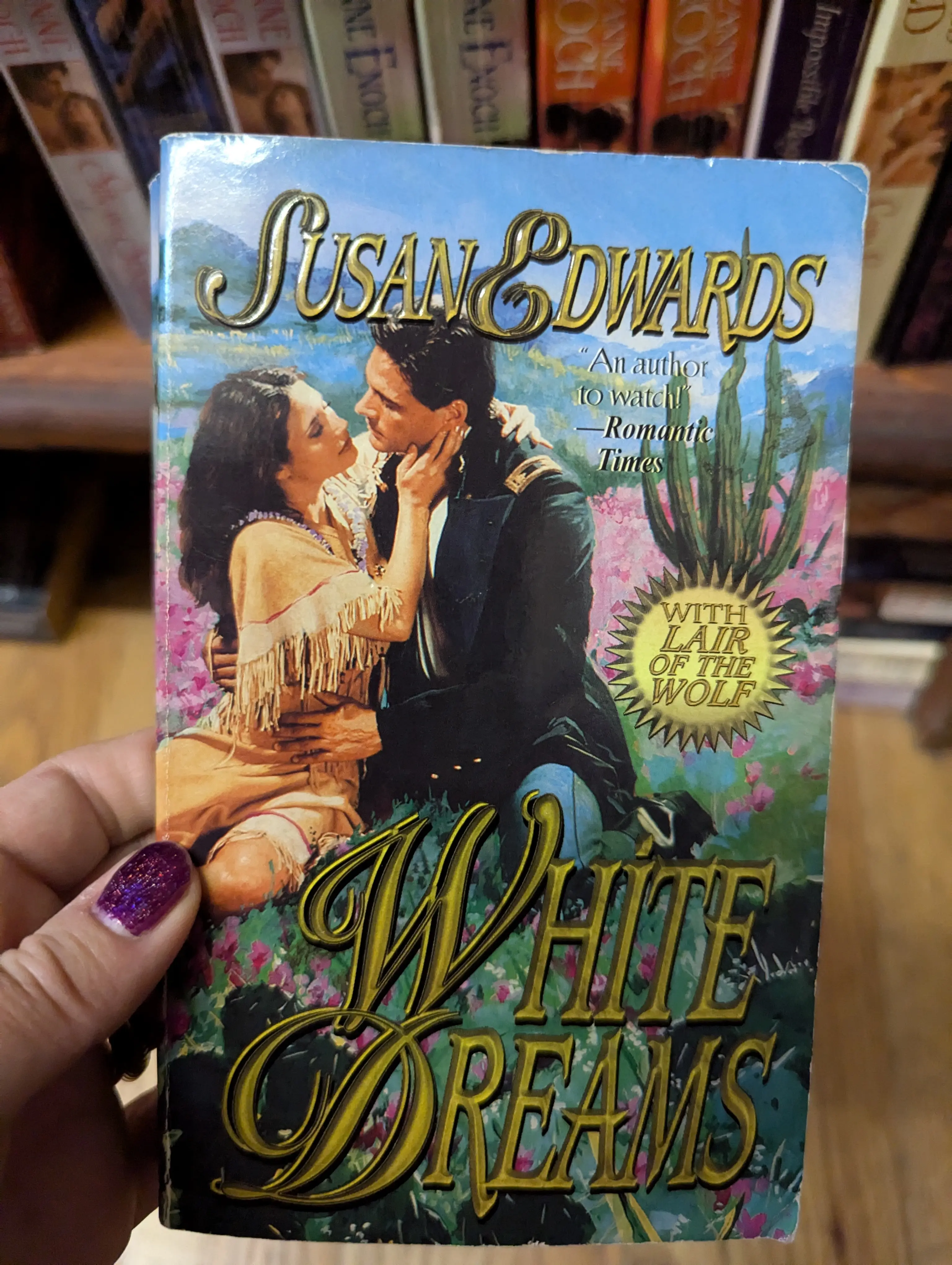 White Dreams by Susan Edwards - a woman in a fringed dress meant to represent an Indigenous person is being embraced by John DeSalvo in a military uniform with epaulets. There's an Erect Cactus behind them. 