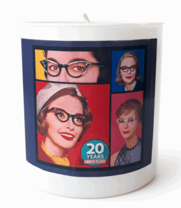 A white jar candle with the SBTB logo of the four 50s ladies with a 20th anniversary insignia on the bottom front 