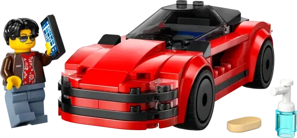 A red lego sports car with a minifigure holding a smart phone a tiny lego sponge and a bottle of cleaner