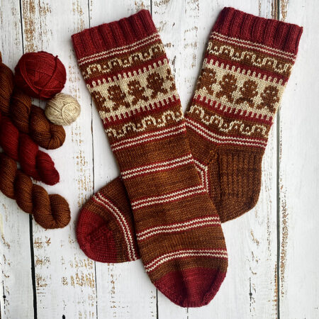A pair of brown and red socks with gingerbread men against a gold background