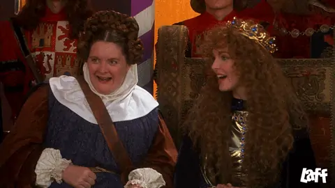 Maid Marian and her handmaid cheer quietly while shaking their fists at a tournament