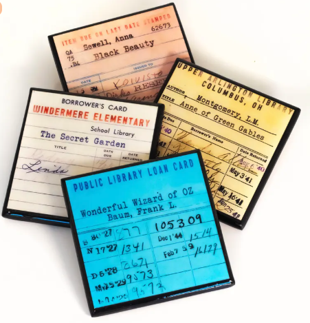Library Card book coasters - four square coasters in blue, yellow, pink, and white, and the books on the front are Black Beauty, Anne of Green Gables, The Secret Garden, and The Wizard of Oz