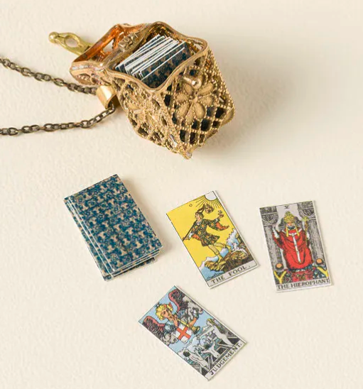 A tiny wire basket charm with miniature tarot cards inside 