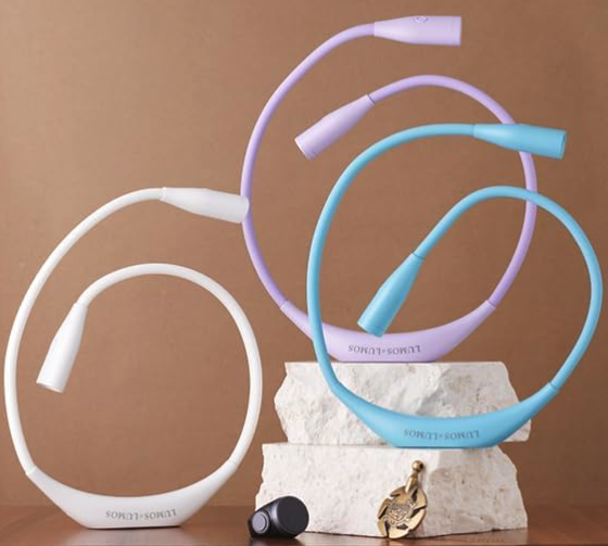 Three Lumos lights in white, pink, and blue. They are u-shaped and have small lamps at the end of each arm 