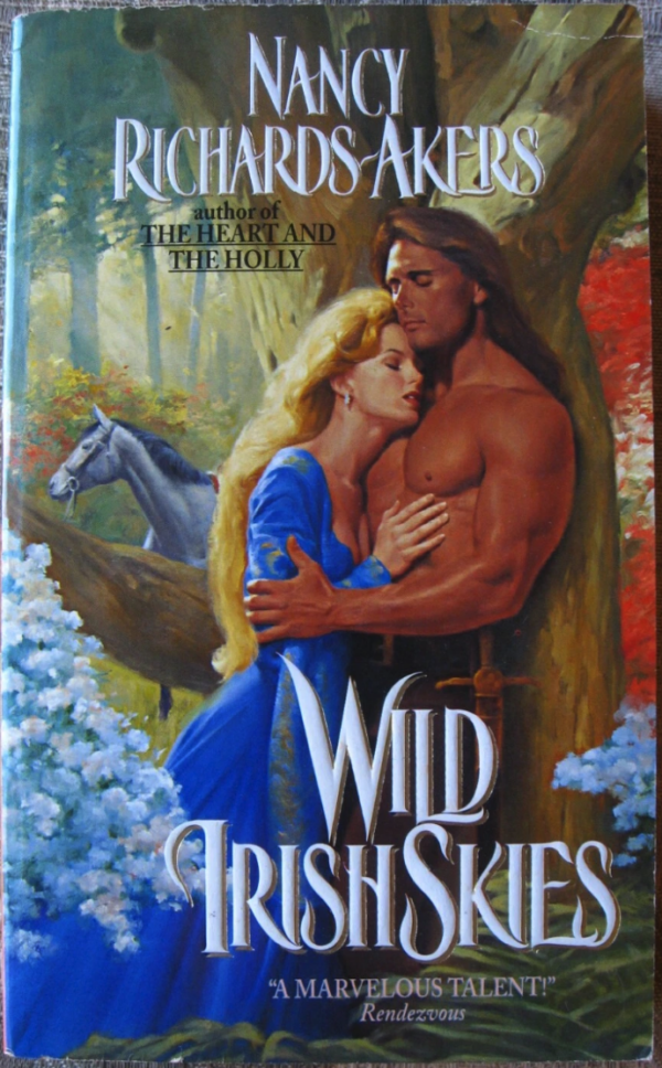 Wild Irish Skies by Nancy Richards-Akers featuring a woman with long blonde hair in a cobalt gown being embraced by a shirtless DeSalvo with long hair, his back against a tree (ow). Behind them a horse looks bewildered.