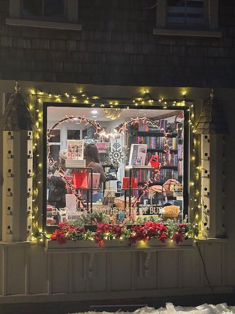 The outside window of Montgomery and Taggert lit up and full of books