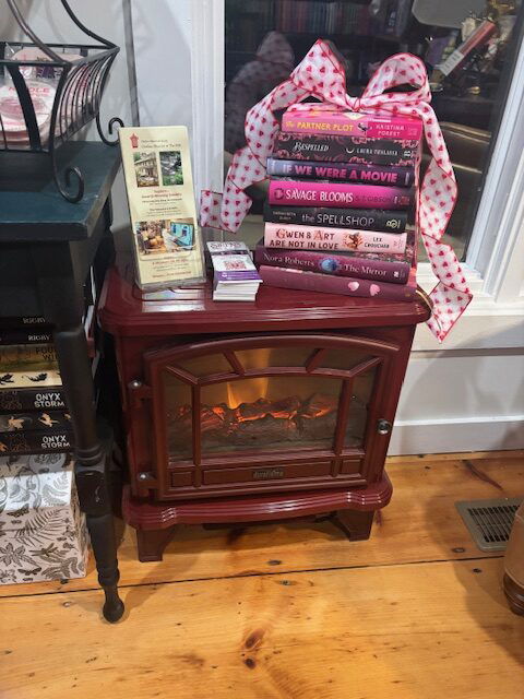 A wood stove with books atop and a fire burning in the grate