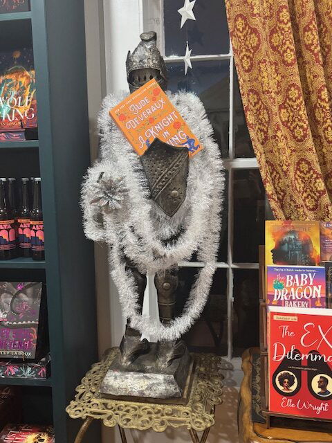 A knight's armor chest and helmet with tinsel and a copy of A Knight in Shining Armor by Jude Deveraux