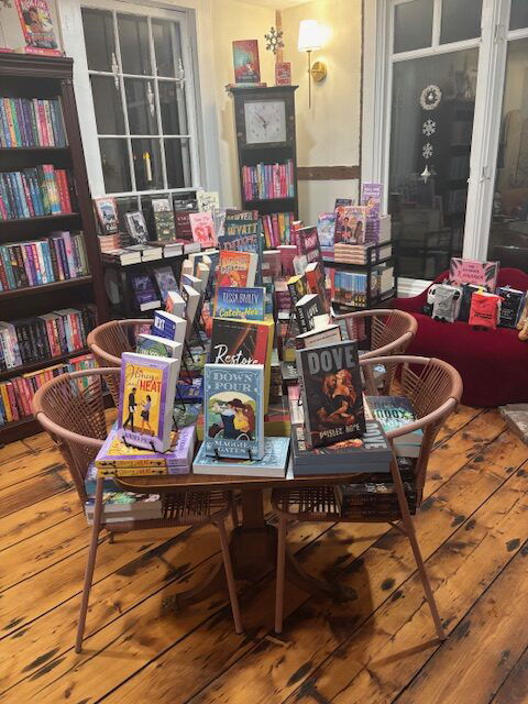 A table and chairs with a tiered stack of romance novels in the center