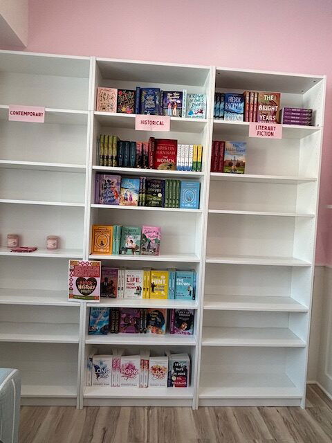 Partially filed bookcases, one labeled Literary Fiction and another labeled historical and an empty one labeled contemporary