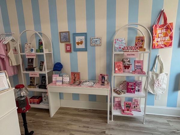 A blue and white striped wall with shelves of different types filled with books