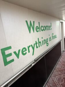 Green Letters on a white wall say Welcome! Everything is fine.