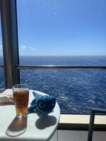 view of the ocean from deck with a table that has a toy lizard and glass of iced tea