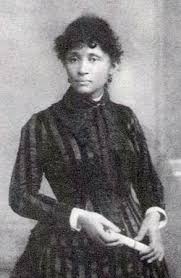Black and white photo of Lucy Parsons, a dark-skinned woman in a striped dress with curly black hair