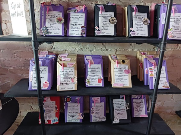 The Blind Date with a Book display, with books wrapped in purple, blue, and gold wrapping paper with stickers on the outside, and a pen tucked into the wrapping fold 