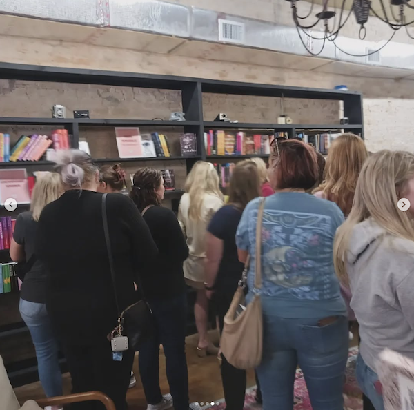 A crowd looking at the shelves with a chandelier visible at the top right 