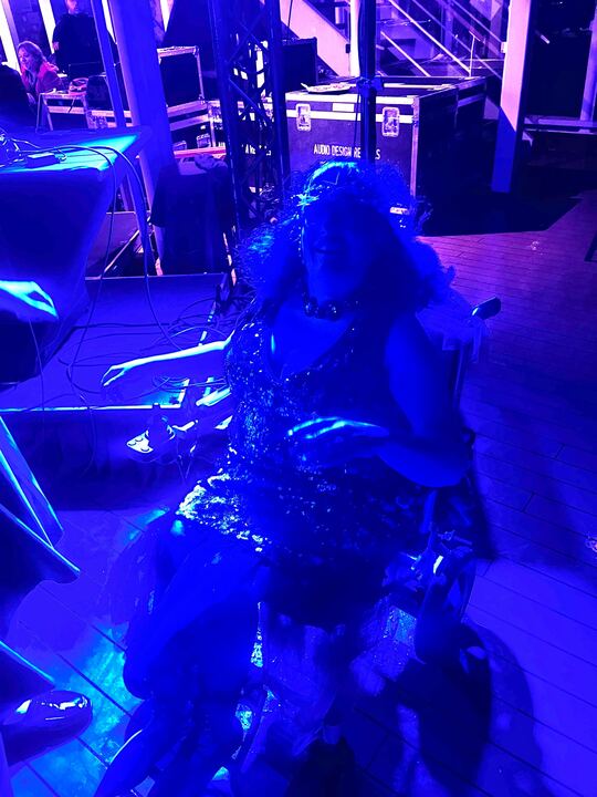 Carrie dancing from her wheelchair, bathed in blue light