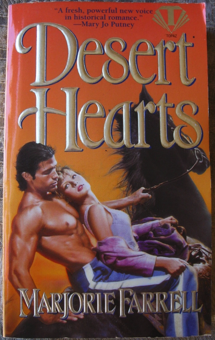 Desert Hearts by Marjorie Farrell A close up of two people on horseback. The horse is facing away, and you can see a white man who is very shiny and muscular and shirtless, wearing blue pants with a white strip down the side that look like tearaway athletic pants. In front of him is a blonde woman wearing magenta lipstick, a purple tank top with a darker purple cardigan down off her shoulders. She has no legs. I mean she might have legs but I don’t know where they are. They aren’t visible. 