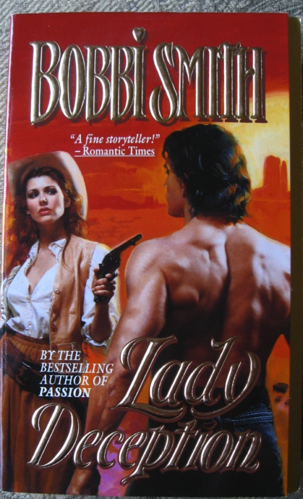 The color cover with a woman wearing a cowboy hat over tousled hair, vest, blouse and shirt wearing a gun belt. She has guns in both hands and one is pointed at shirtless DeSalvo in jeans with his back to the viewer. 